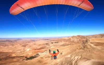 Paraglider flying above arid landscape